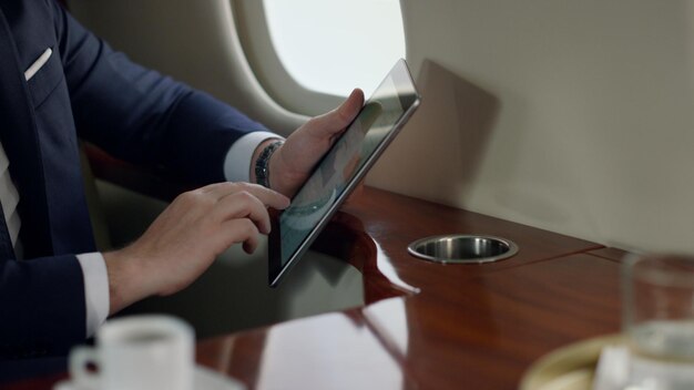 Foto primo piano del passeggero che tiene in mano il tablet schermo toccante per un uomo d'affari elegante