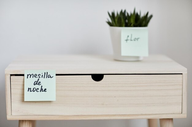 Closeup of pastel colored wooden nightstand with notepaper stuck to it