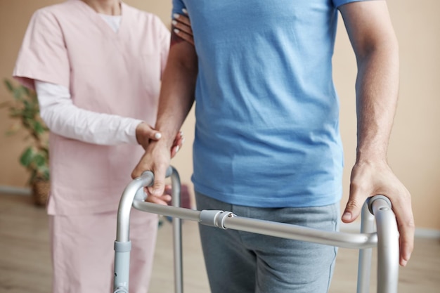 closeup of patient walking with walker in hospital together with doctor