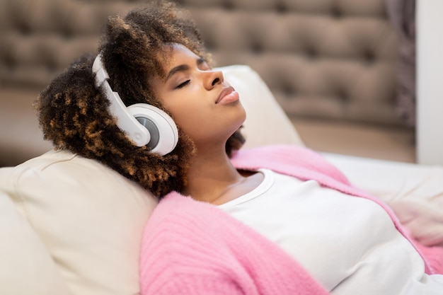 Closeup of peaceful millennial black woman using headphones