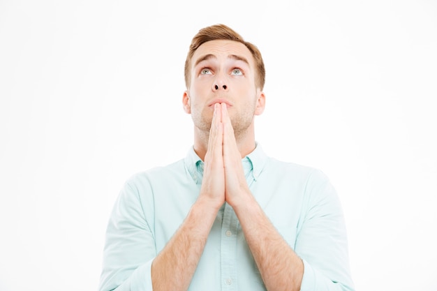 Closeup of peaceful young businessman praying and looking up