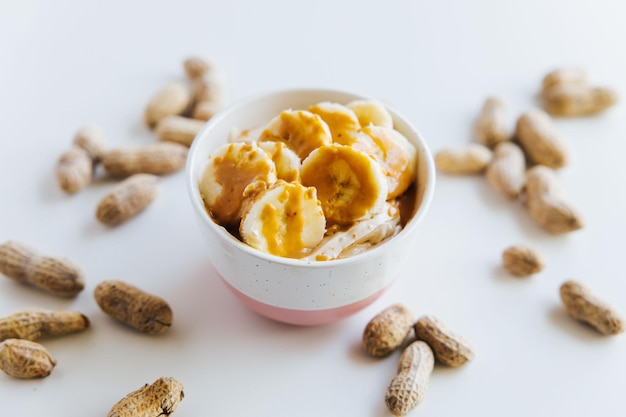 Closeup of a Peanut Butter Banana Pudding in a bowl surrounded by peanuts