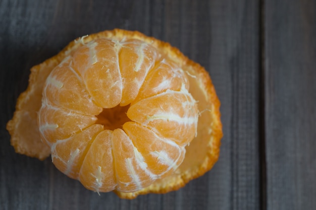 Closeup of peeled bold mandarine tangerine on wooden background