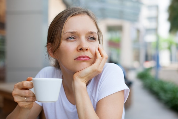 屋外でコーヒーを飲む幸せな女性のクローズアップ