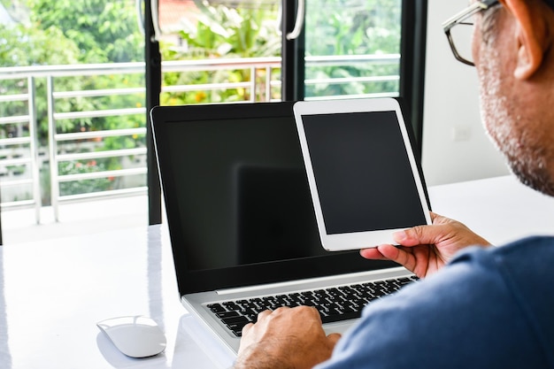 Closeup People using the device home A man holds a tablet to use the internet in the living room at home during the day Color tablet for sale blank black screen for design and lettering Copy space