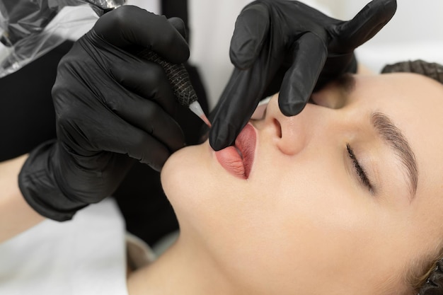 Closeup of the permanent makeup procedure Lip makeup in the cosmetologist's salon