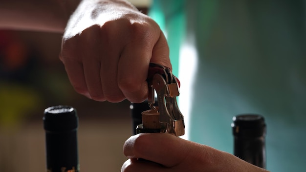 Closeup of person hands opening bottle of wine with corkscrew sommelier or waiter in restaurant