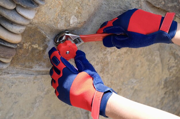 Closeup of person hands in work gloves repairing tap using\
wrench central water supply system