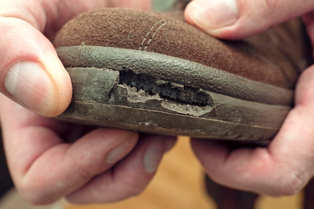 Closeup of a person holding shoe with torn sole