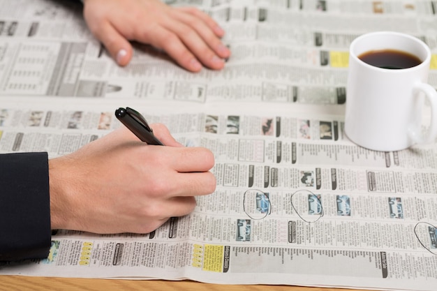 Photo closeup of a person looking at classified ads