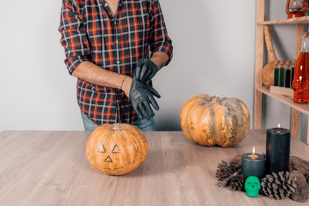 A closeup of a person wearing latex gloves and preparing to carve a pumpkin for Halloween