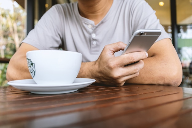 Closeup of phone in the hands of a man sitting in a coffee shop