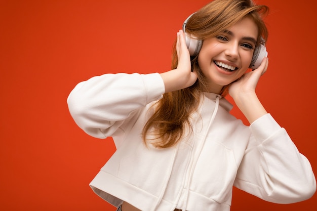 Closeup photo of attractive positive smiling young blonde woman wearing white hoodie isolated over