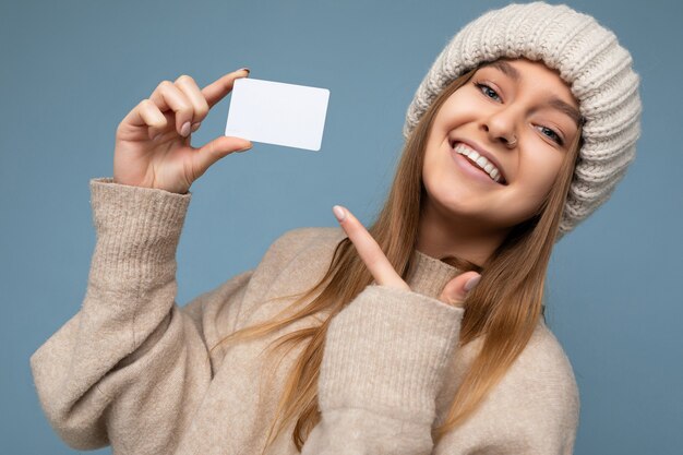 Foto primo piano di una giovane donna sorridente positiva sexy attraente che indossa un maglione beige e lavora a maglia