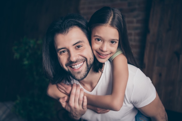 Closeup photo of beautiful little adorable girl and handsome young daddy hugging piggyback dreamy smile spend weekend time homey domestic house room indoors