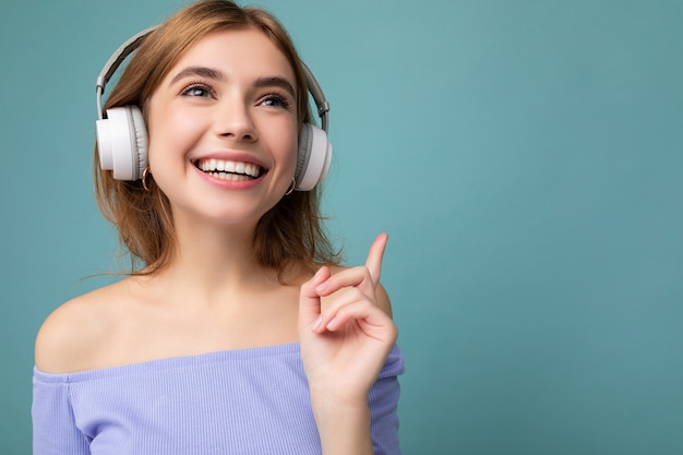 Primo piano di bella giovane donna bionda sorridente positiva che indossa un top corto blu isolato sopra