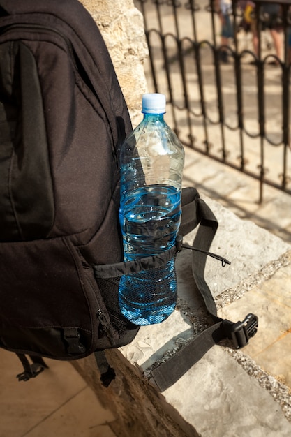 Foto primo piano della bottiglia d'acqua nella tasca dello zaino turistico