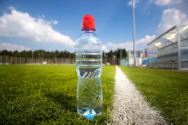 Крупным планом фото бутылки воды футбольного поля во время матча