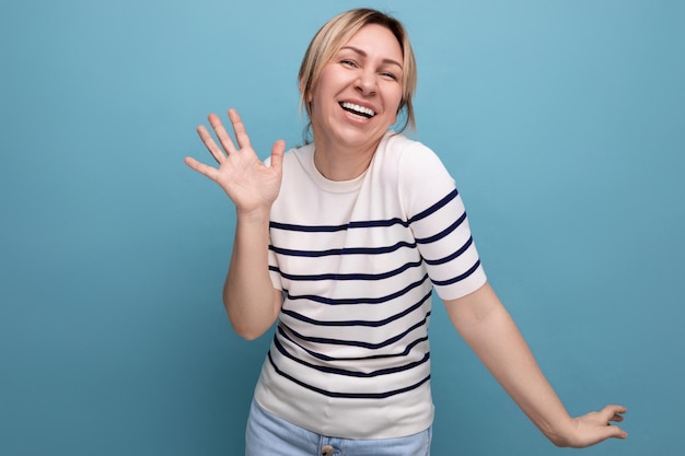 Closeup photo of a cheerful blond girl in a striped sweater on a blue background