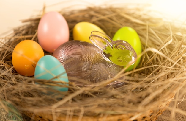 Closeup photo of colorful Easter eggs and glass rabbit lying in nest