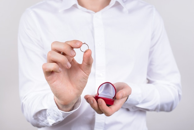 Closeup photo cropped picture of happy cheerful excited glad positive optimistic guy holding small little ring in hand with fingers isolated grey background