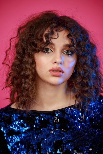 Closeup photo of curlyhaired girl on pink background High quality photo