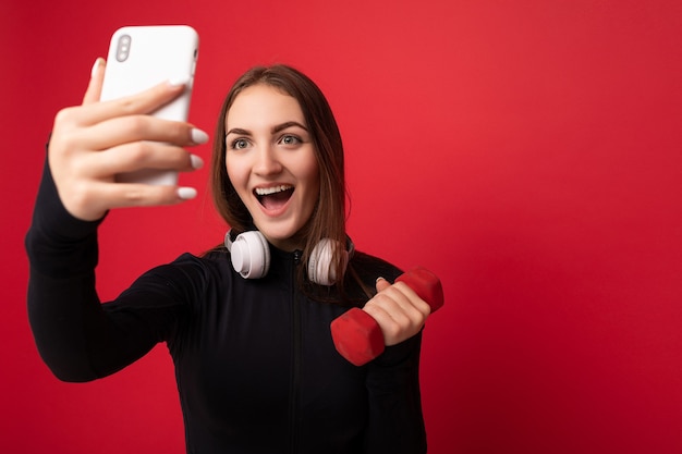 Primo piano di una bella e positiva giovane donna bruna che indossa abiti sportivi neri