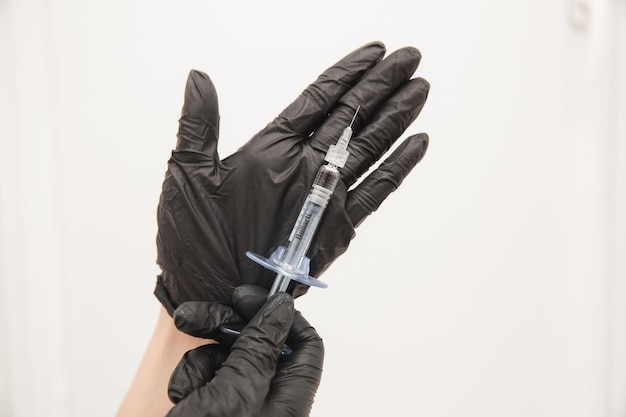 A closeup photo of doctors in disposable latex rubber gloves holding a syringe shows the injection in an isolated background