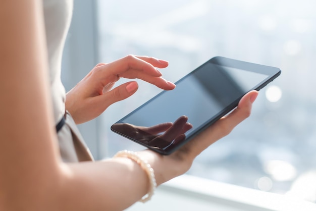 Closeup photo of female hands working with tablet computer Woman using social network texting and blogging