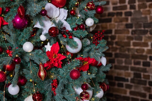 Closeup photo of festive balls on fir tree in living room white red christmas decorations hanging on...