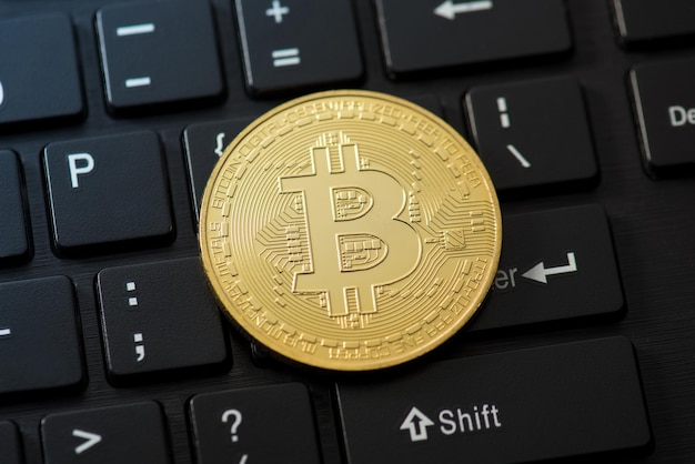 Closeup photo of gold coin with bitcoin symbol on black keyboard background