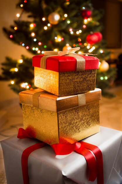 Closeup photo of golden and red gift boxes under Christmas tree