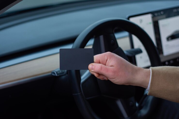 Photo closeup photo of a hand gripping a electric cars steering wheel with a tablet inside the cabin