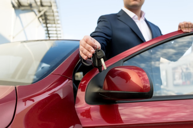 Closeup photo of handsome car salesman giving keys