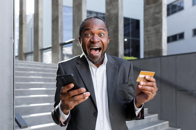 Closeup photo happy and shocked african american man in suit standing outside bank office he holds a