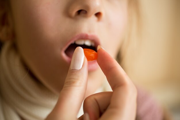 Closeup photo of little girl taking medicine in pill