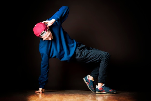 Closeup photo of male break dancer performing stance against dark background b