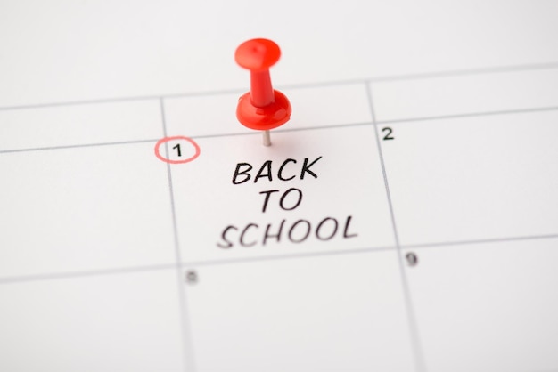 Closeup photo of mark on calendar at first inscription back to school with red pushpin