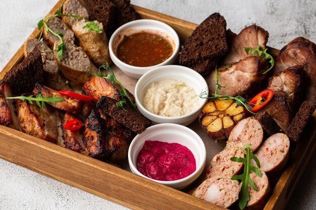 Closeup photo of mixed grilled meat platter Beef pork poultry sausages grilled garlic chili pepper different sauces on marble background