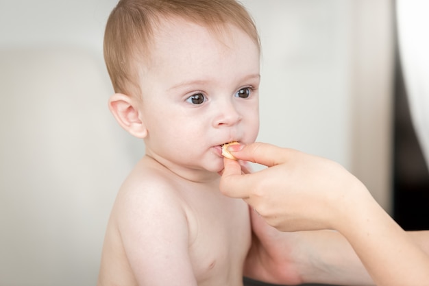 Closeup photo of mothers hand giving her baby son a biscuit