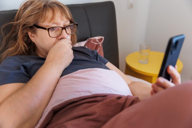 写真 自宅で病気の女性のクローズ アップ写真は鼻水がひどく、ベッドに横たわっています。