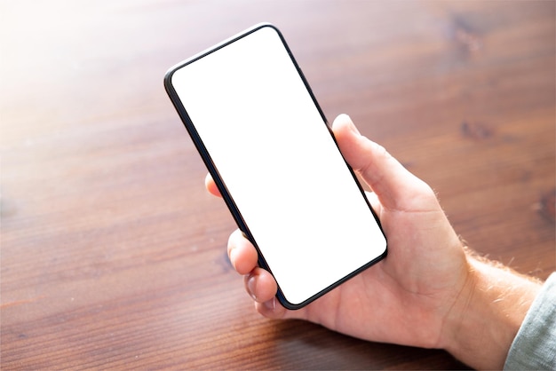 Closeup photo of person holding mobile phone in hand blank
white screen mockup