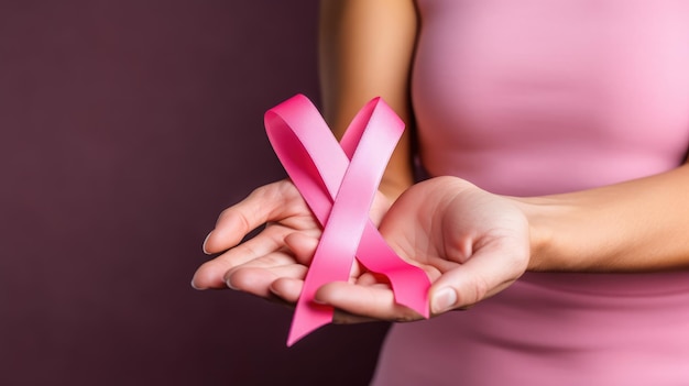 A closeup photo of a pink ribbon being held in the hands of a woman