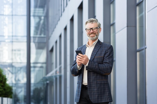 Closeup photo portrait of an older grayhaired man in a suit and glasses standing outside an office