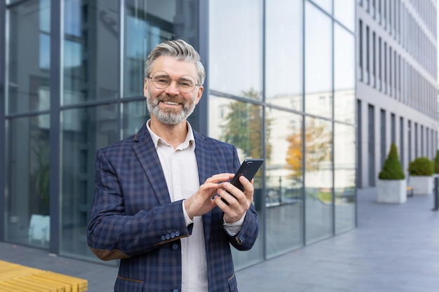 Closeup photo portrait of an older grayhaired man in a suit and glasses standing outside an office