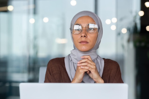 Closeup photo portrait of a young beautiful arab student woman in a hijab sitting at the table