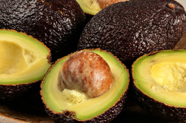 Closeup photo - ripe brown avocados hass bilse variety halved, detail on fruit seed.