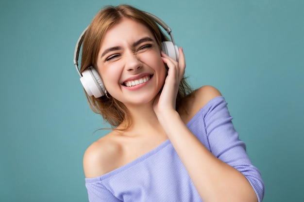 Closeup photo of sexy pretty happy smiling young blonde woman wearing blue crop top isolated over