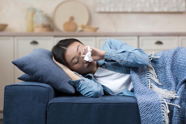 Closeup photo of a sick woman lying on the sofa at home having a fever and flu an asian woman lying