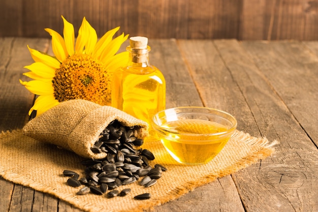 Closeup photo of sunflower oil with seeds on wooden background. Bio and organic product concept.